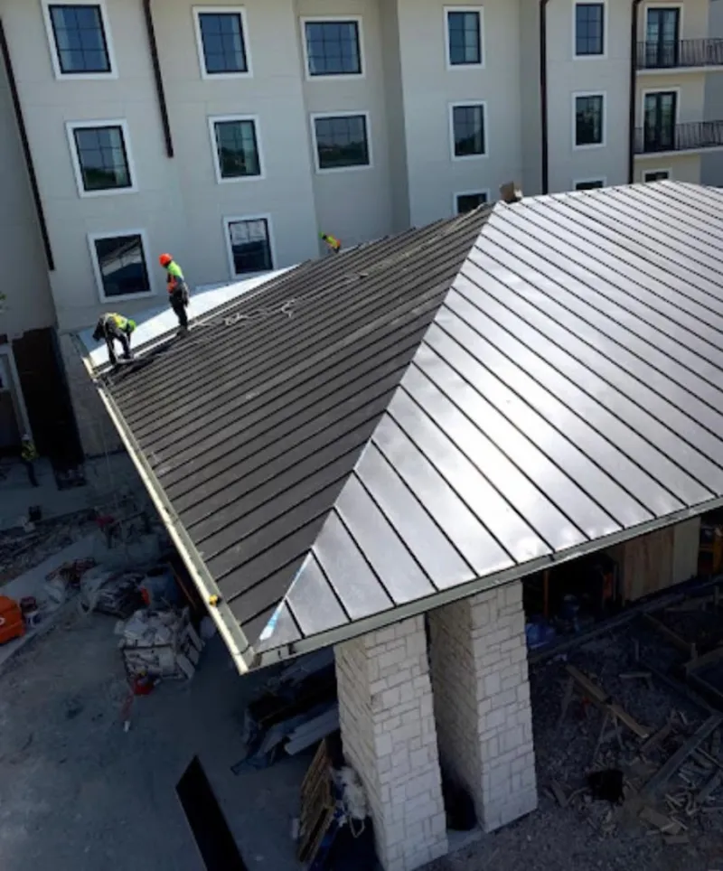 Crew installing standing seam metal roof panels on a commercial project in McHenry